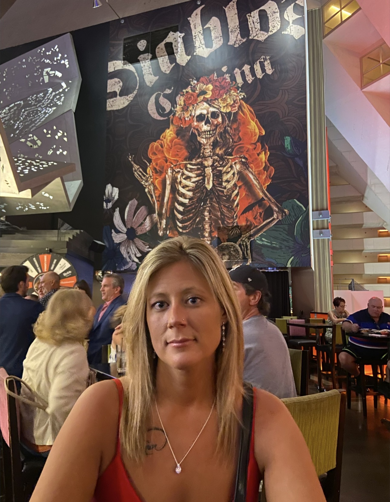 Woman seated inside Diablo’s Cantina at Luxor Las Vegas with colorful skeleton artwork behind her