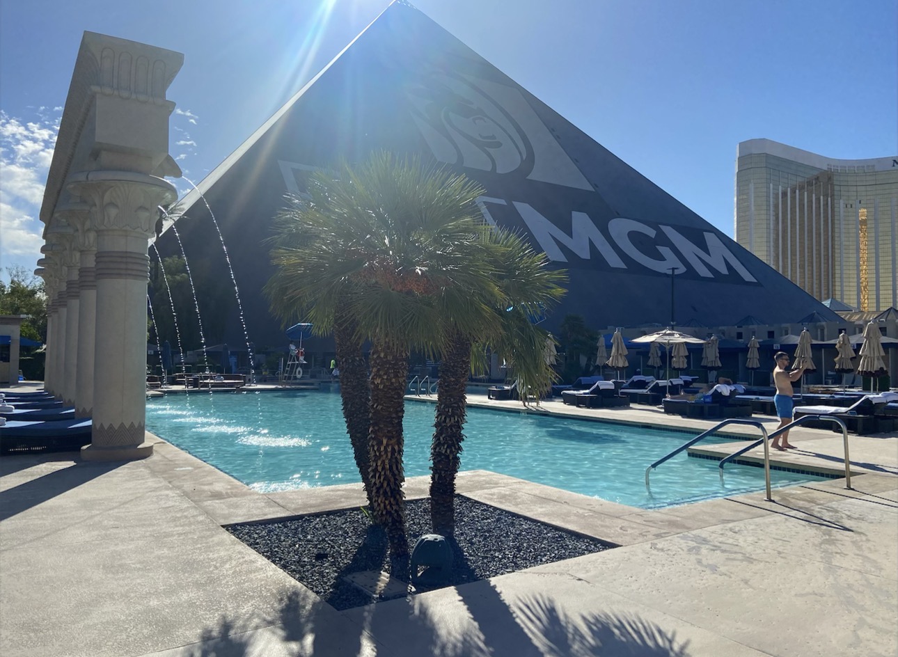 Luxor Las Vegas swimming pool with palm trees and the famous black pyramid in the background.