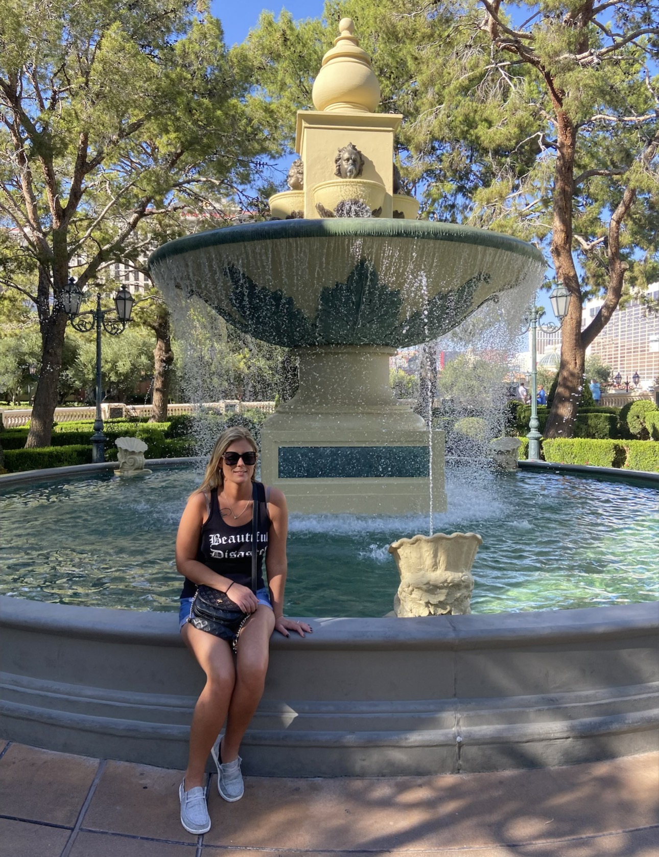 Nikki sitting beside a decorative fountain surrounded by landscaped gardens in Las Vegas.